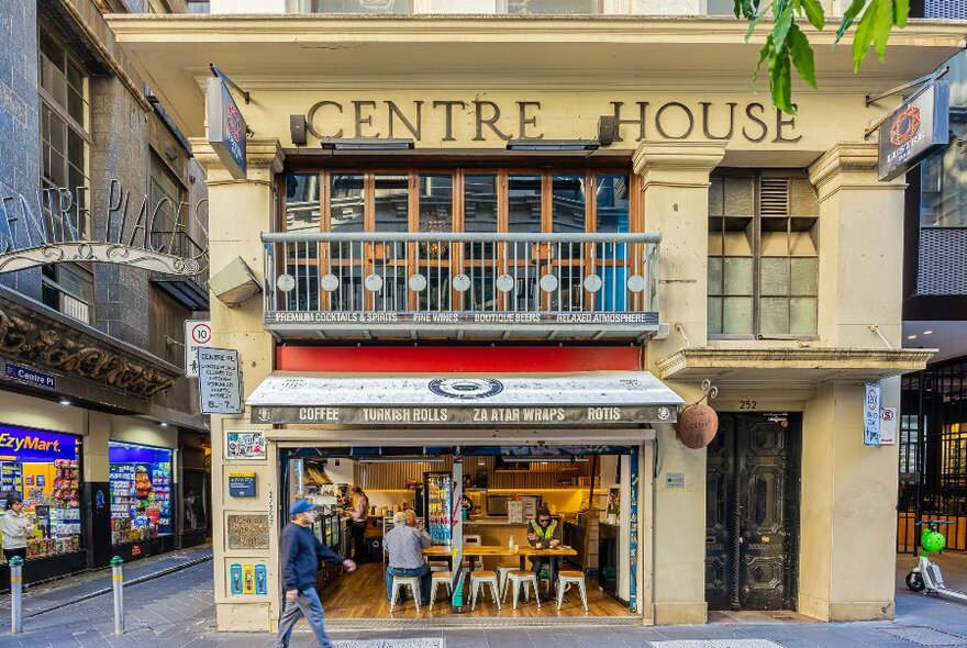 A person dining at a large table in small corner cafe on a laneway.