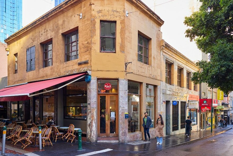 Two people are walking into a corner wine bar