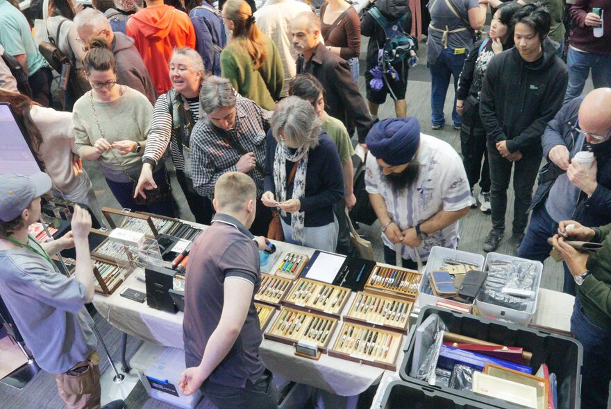 Customers looking at pen and stationery supplies for sale at an exhibition stall.