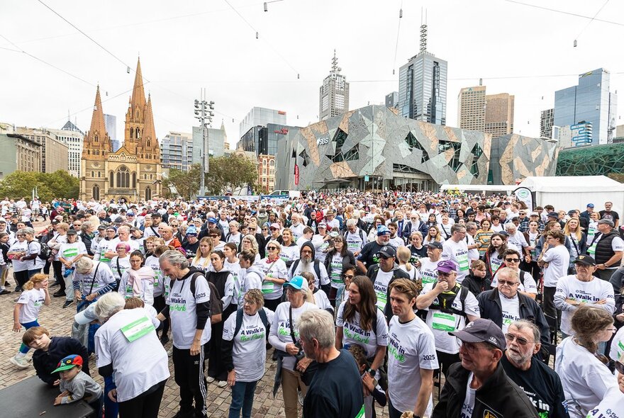 A large crowd of people at Melbourne's Fed Square, all wearing white t-shirts.