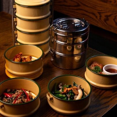 Bowls of Thai food served in traditional stacked enamel dishes.
