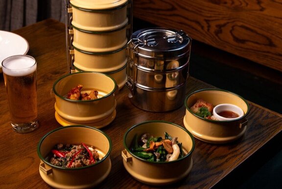 Bowls of Thai food served in traditional stacked enamel dishes.