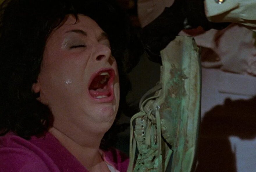A still from the movie Polyester showing a woman's face crying in anguish with her mouth open and eyes closed. 