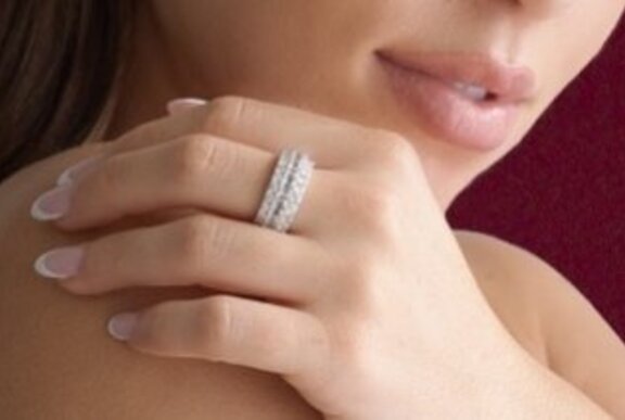 Close up of a woman's hand held against her lower face, highlighting a diamond ring on her middle finger.