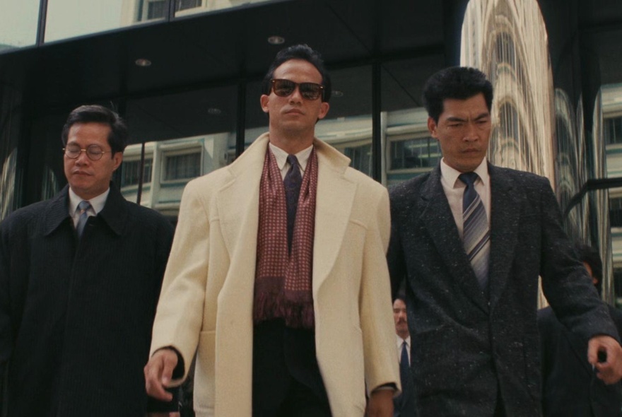 A still from the 1986 movie A Better Tomorrow, with three men in suits walking purposefully towards the camera, shot from below.