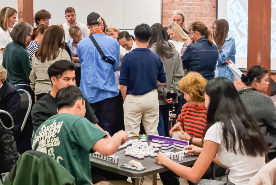 People seated around tables playing the game mahjong at the Chinese Museum.