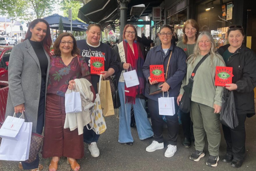 A tour group holding merchandise bags and books, standing in a street.