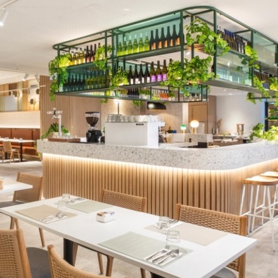 Hotel restaurant with central bar surrounded by tables and chairs.