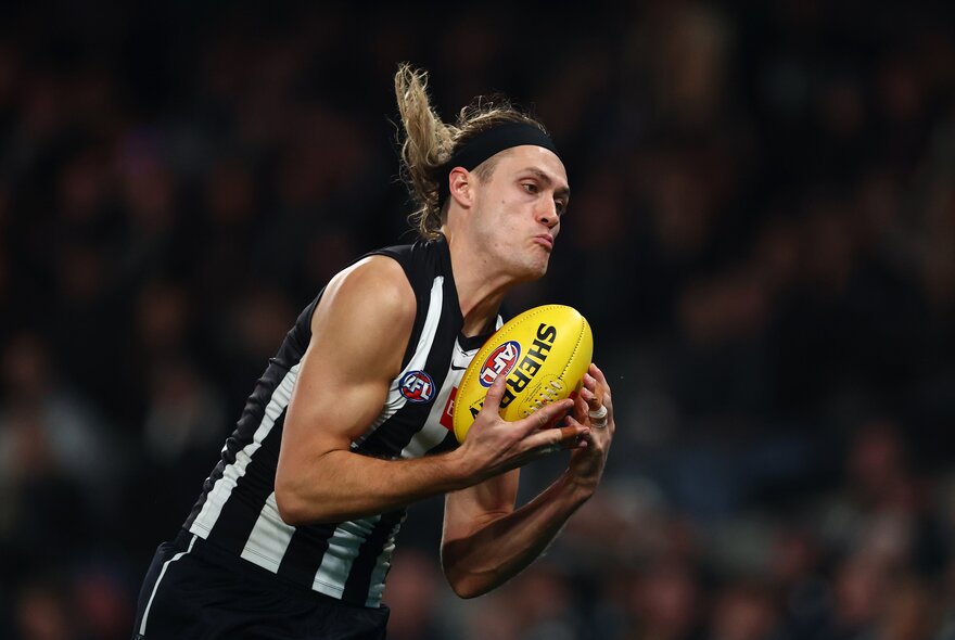 Collingwood AFL football player catcing a ball during a match.