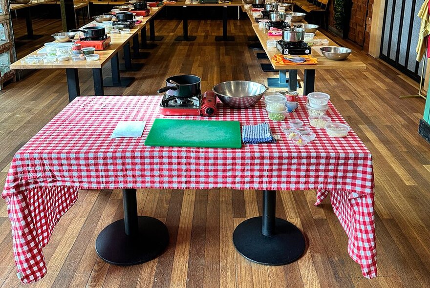 Tables with cooking workshop utensils, one table with gingham cloth.