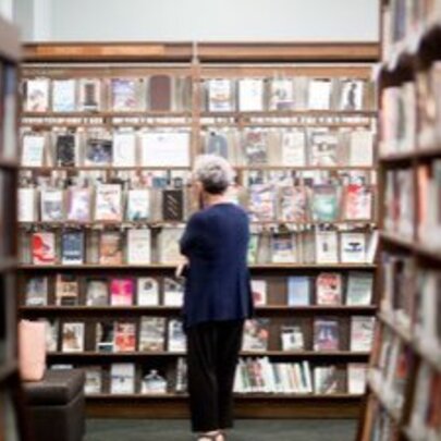 A person perusing books on shelves in Melbourne Athenaeum Library.