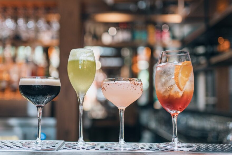 Four cocktails lined up on a bar.