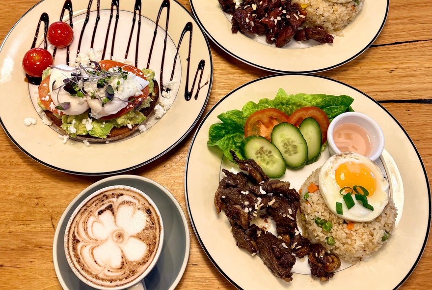 Filipino breakfast dishes of food includig rice and eggs, with cappuccino.