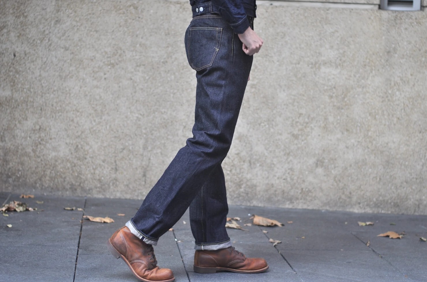 A person is wearing a pair of dark denim jeans
