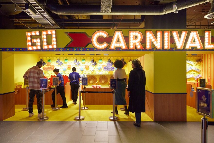 Two friends looking at a yellow carnival game.