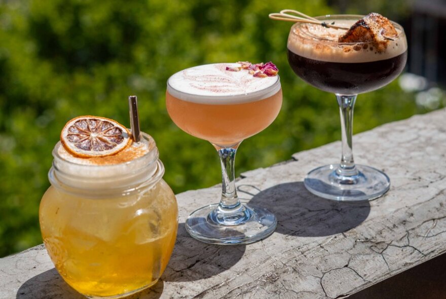 Three different cocktails balanced on a table.