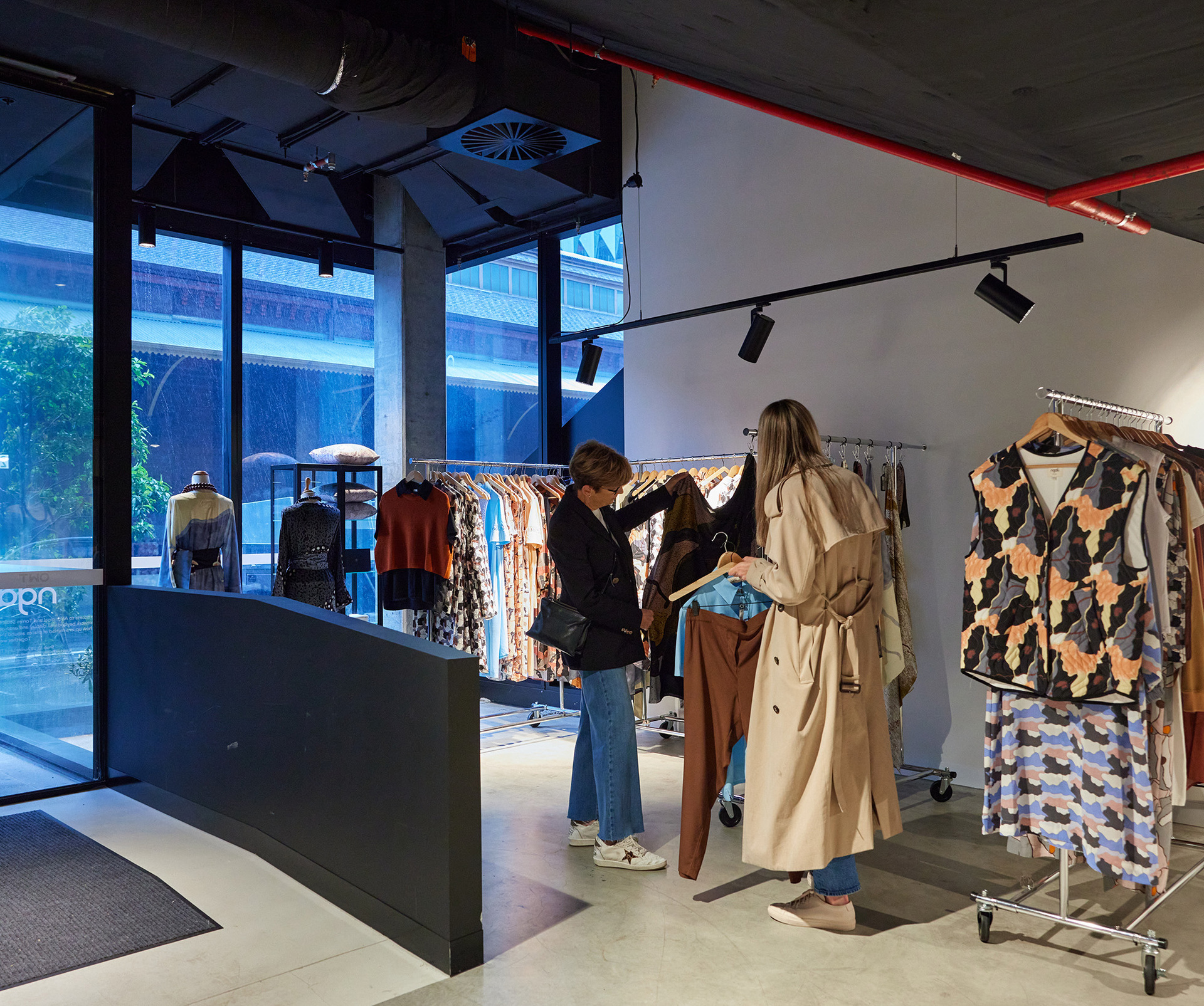 Two friends are browsing clothes inside a women's clothing store