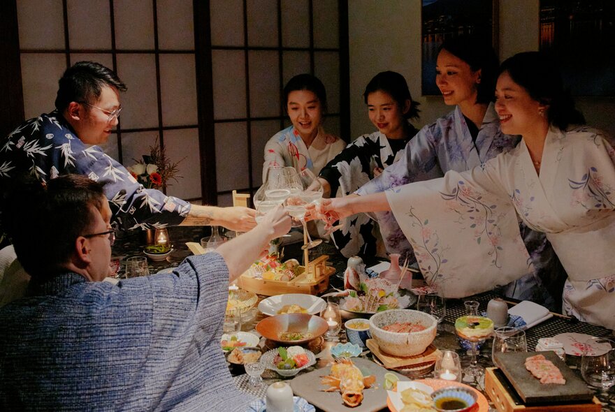 A group of people dressed in kimono and celebrating with a feast of Japanese food in a private restaurant dining room.