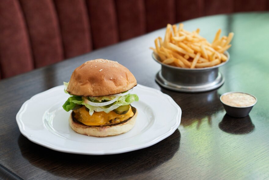 A burger on a plate and a bowl of fries