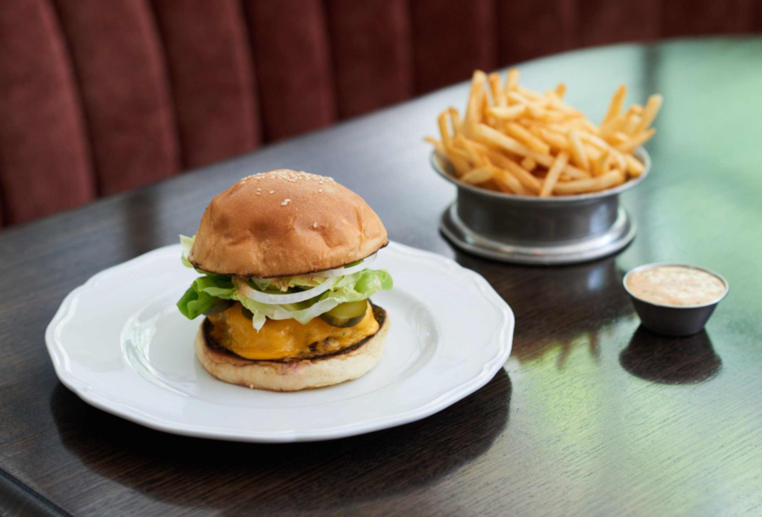 A burger on a plate and a bowl of fries