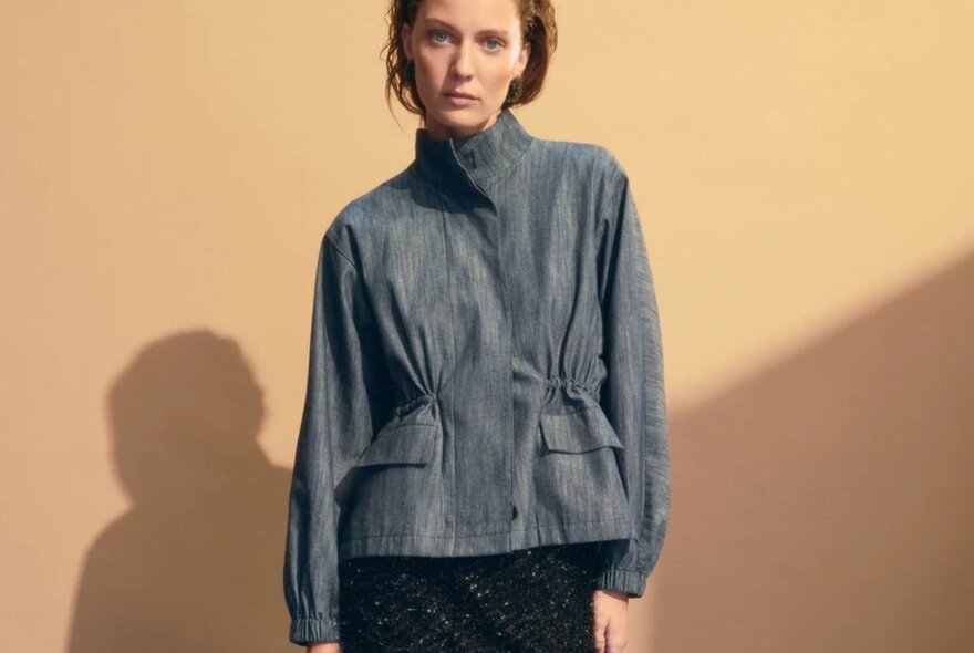 A model is wearing a denim jacket with a high neck