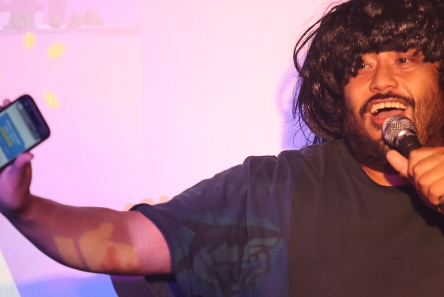 Comedian David Correos performing stand up on a stage, holding a microphone.