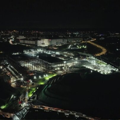 An aerial, high-angle night photograph of a large, brightly lit industrial or commercial complex.