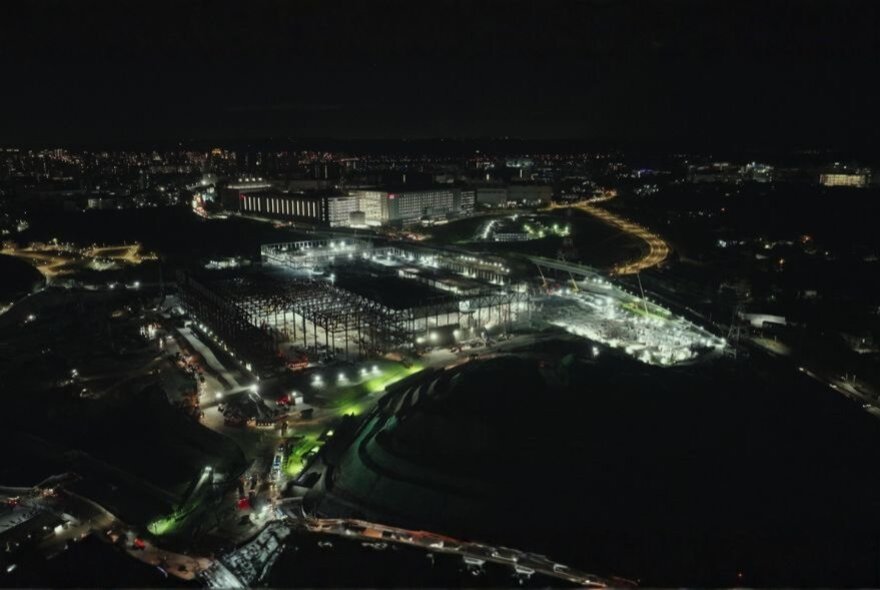 An aerial, high-angle night photograph of a large, brightly lit industrial or commercial complex.