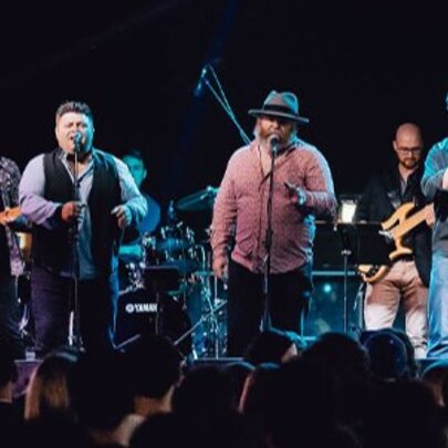 A large band performing on stage in front of an audience. 