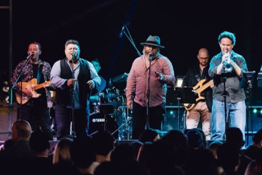 A large band performing on stage in front of an audience. 