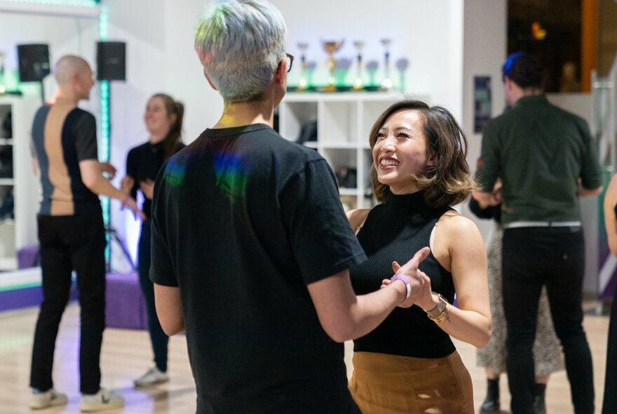 A couple holding hands learning to dance with other coples.