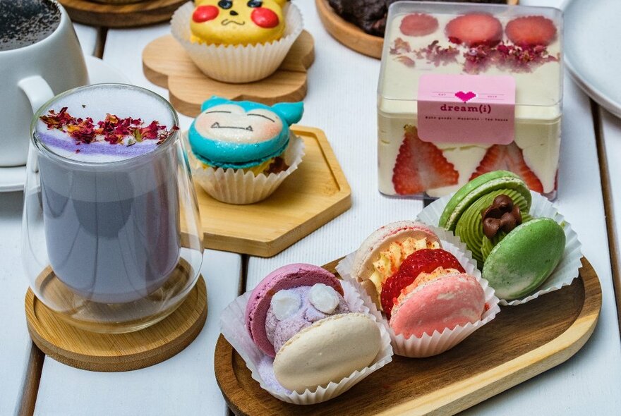 A table with macarons, ube latte, and cakes