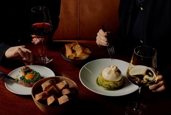 Wine and share plates on a dimly lit restaurant table.