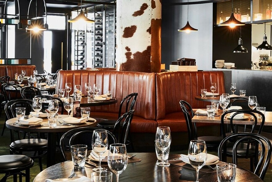 Interior of Asado showing tables set for dinner, chairs and banquettes.