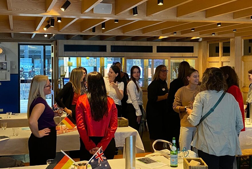 A group of women standing in a room networking. 