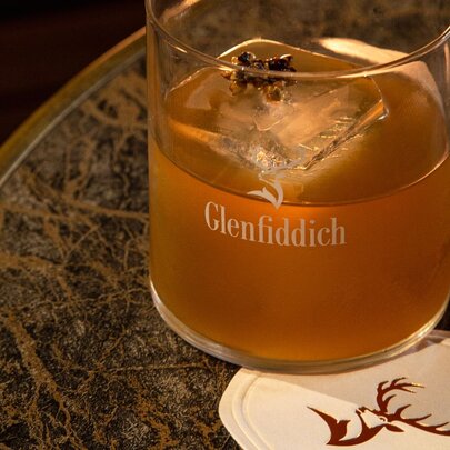 A glass of Glenfiddich whisky on a coaster on a marble table top.