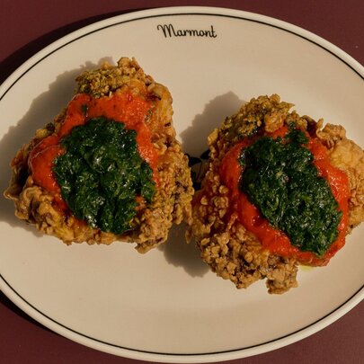 A plate of fried chicken with a red and green layered sauce.