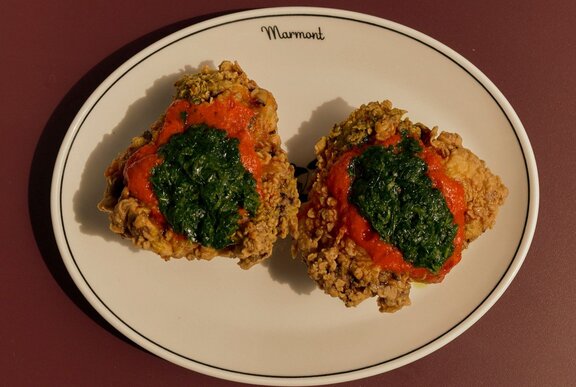 A plate of fried chicken with a red and green layered sauce.