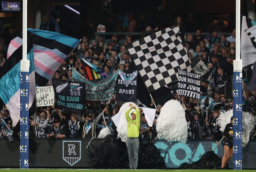 Port Adelaide flags and bunting surround the goalposts during an AFL football game.