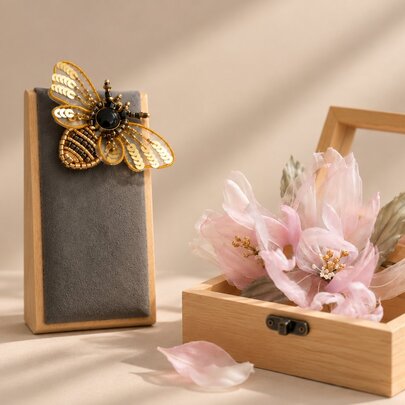 Wooden display cases showcasing an embroidered bee and a delicate hand-made flower.