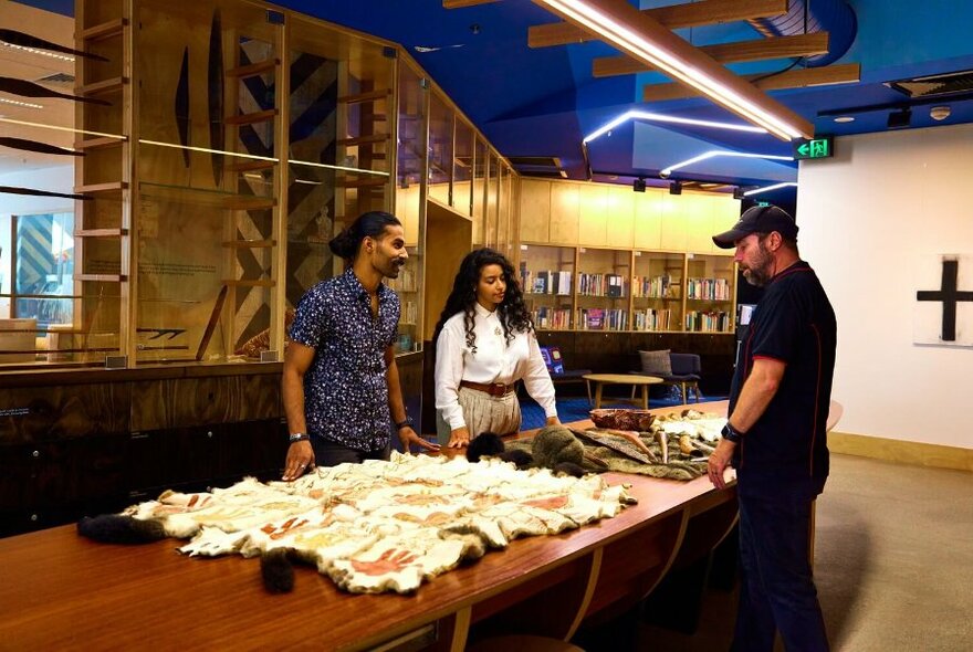 Three people looking at Indigenous artefacts on a table at the Koorie Heritage Trust.  