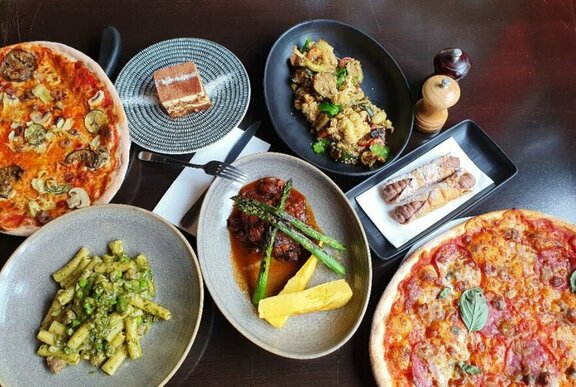 Restaurant table set with a range of Italian dishes including pizza.