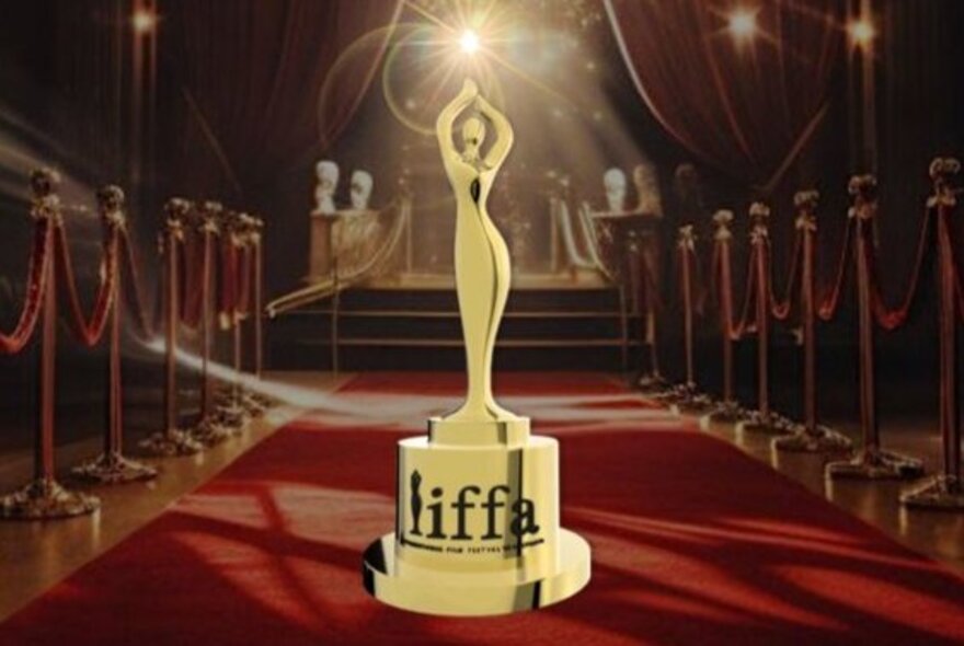 Film industry award statuette in a red carpet cinema setting.