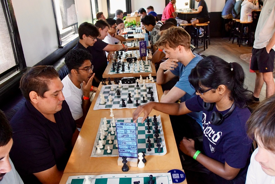 A social chess gathering where people are playing chess matches in an indoor setting of a bar.