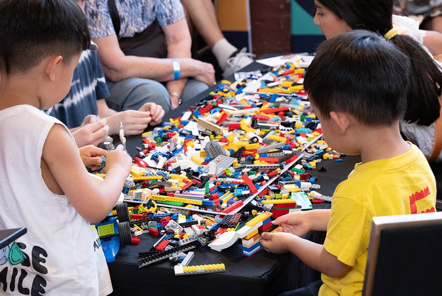 Children playing at a table piled with Lego bricks.