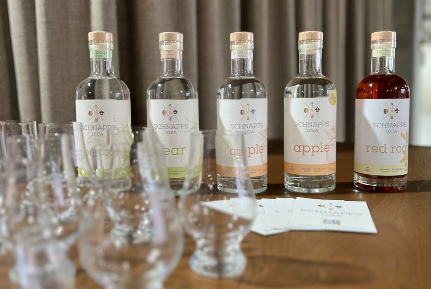 Bottles of Schnapps displayed on a table with empty glasses in the foreground.