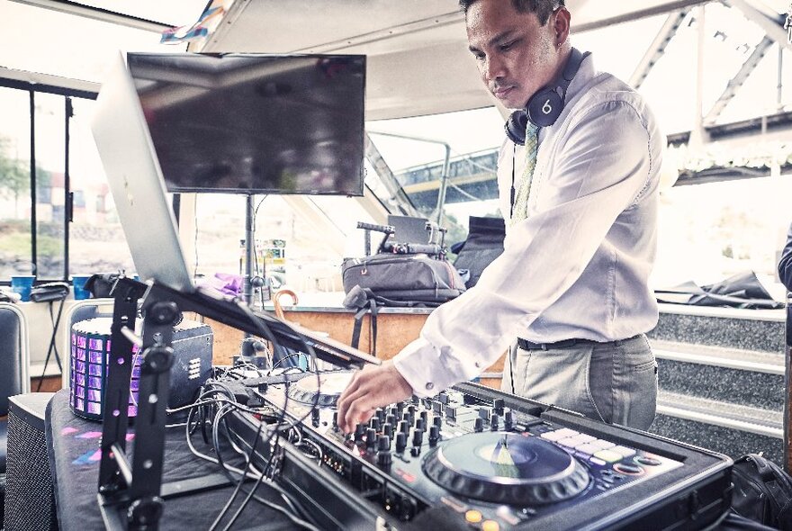 A DJ at a mixing desk on a large boat.