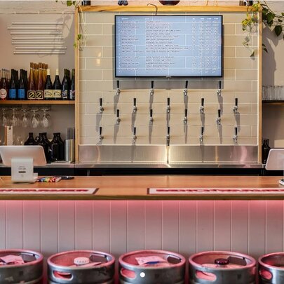 The interior of a craft brewery, with multiple beer taps on the rear wall.