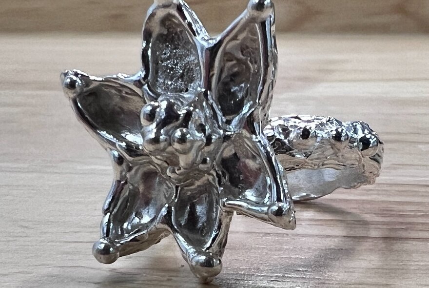 A handcrafted silver ring with a large flower.