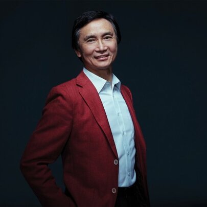 Li Cunxin, wearing a red jacket and white shirt.